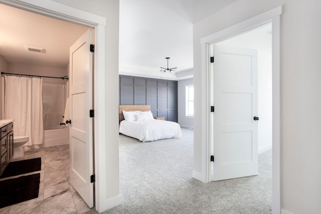 carpeted bedroom with visible vents, baseboards, and connected bathroom