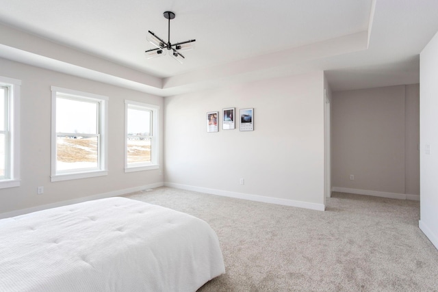 bedroom with a tray ceiling, baseboards, a notable chandelier, and light carpet