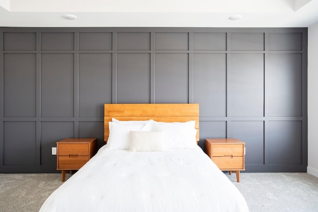 bedroom with light colored carpet and a decorative wall