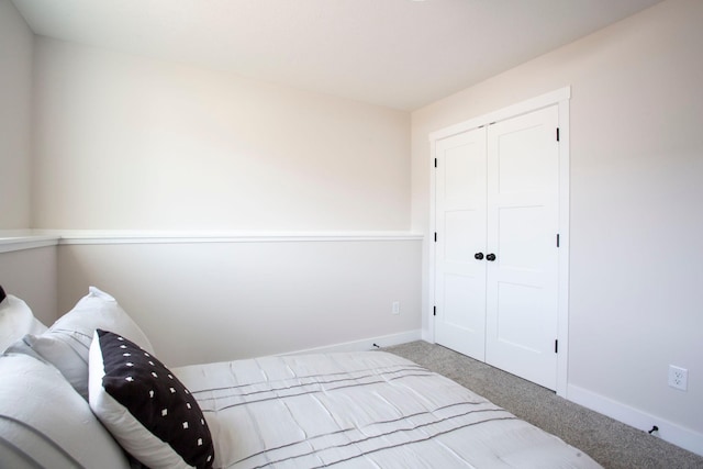 carpeted bedroom with baseboards and a closet