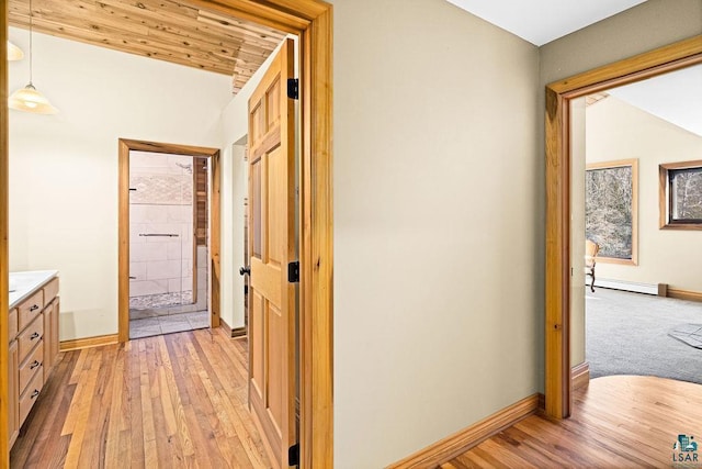 hallway with a baseboard radiator, baseboards, light wood-style floors, and wooden ceiling