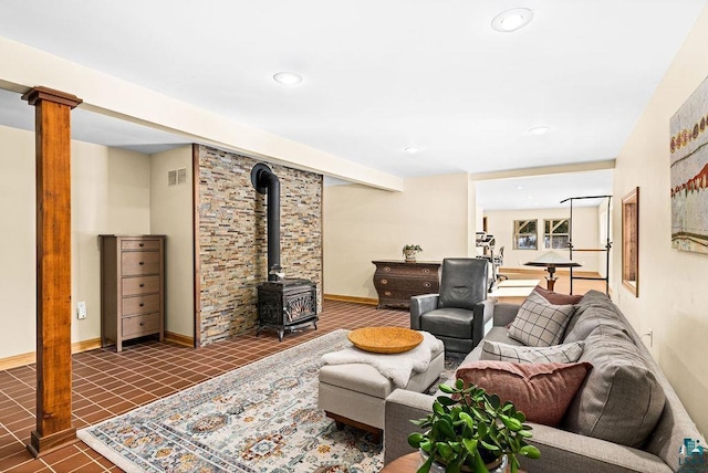 living area with tile patterned flooring, visible vents, a wood stove, and baseboards