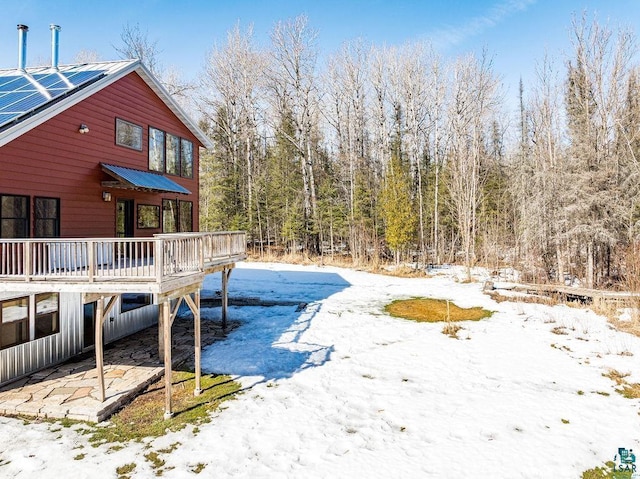 yard covered in snow featuring a wooden deck and a forest view