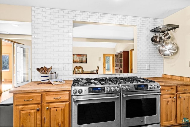 kitchen with range with two ovens, butcher block countertops, tasteful backsplash, and brown cabinets