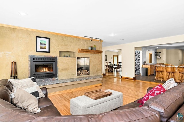 living area with a high end fireplace, wood finished floors, bar area, baseboards, and recessed lighting