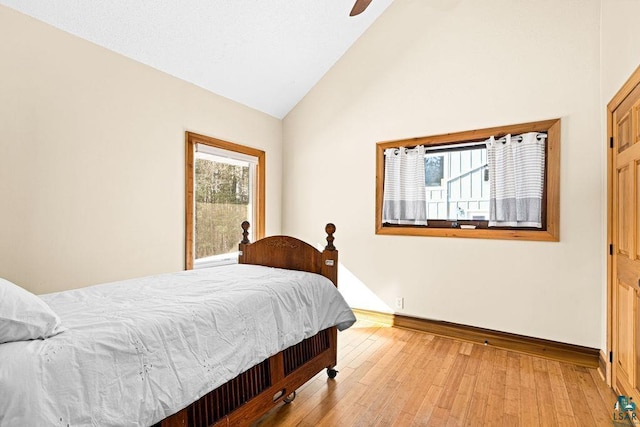 bedroom featuring multiple windows, baseboards, light wood-type flooring, high vaulted ceiling, and a ceiling fan