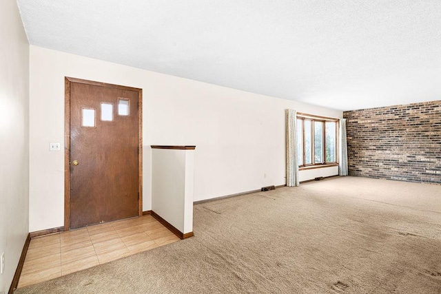 tiled foyer entrance with a textured ceiling, carpet, visible vents, and baseboards