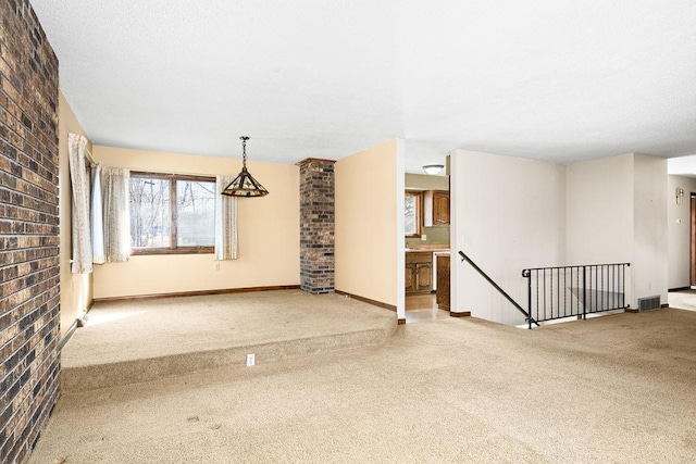 unfurnished room featuring baseboards, visible vents, brick wall, a textured ceiling, and carpet flooring