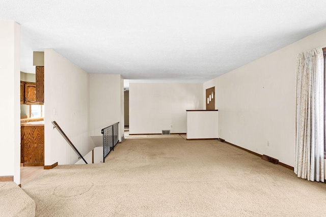 empty room featuring carpet flooring, visible vents, and baseboards