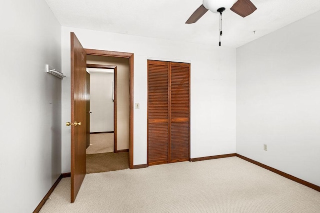 unfurnished bedroom with a closet, light colored carpet, baseboards, and ceiling fan