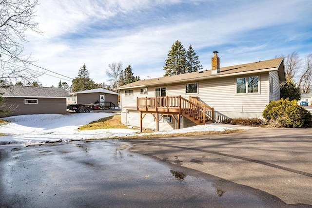 single story home with a wooden deck and a chimney