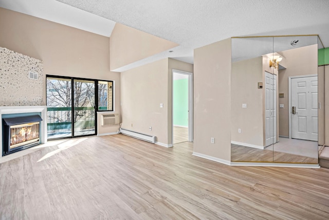 unfurnished living room with baseboards, an AC wall unit, baseboard heating, wood finished floors, and a glass covered fireplace