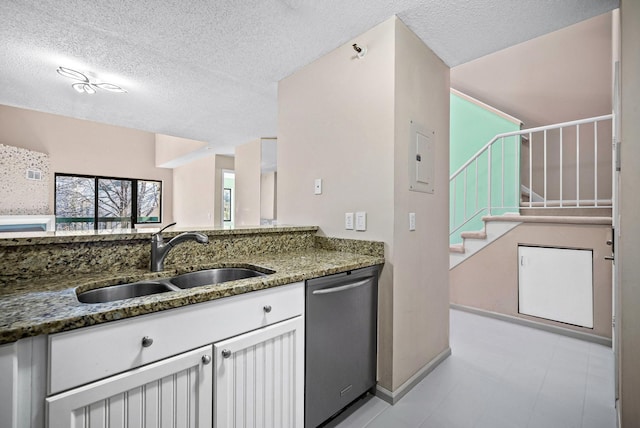 kitchen featuring a sink, stone countertops, stainless steel dishwasher, a textured ceiling, and white cabinetry