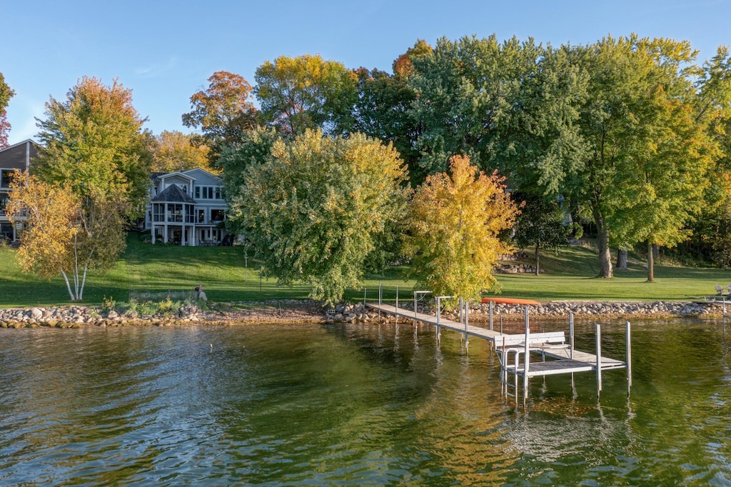 view of dock with a lawn and a water view