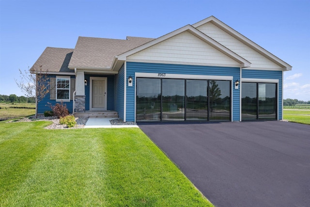 view of front facade featuring a front lawn, driveway, and a shingled roof