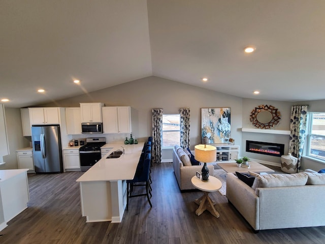 kitchen with open floor plan, a breakfast bar, light countertops, appliances with stainless steel finishes, and a sink