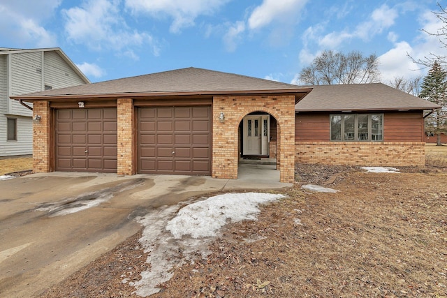 view of front facade with a garage, brick siding, driveway, and a shingled roof