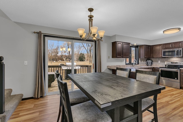 dining room featuring an inviting chandelier, a healthy amount of sunlight, light wood-type flooring, and baseboards