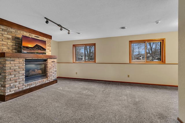 unfurnished living room with baseboards, visible vents, a textured ceiling, a brick fireplace, and carpet flooring