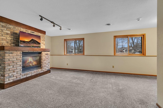 unfurnished living room featuring visible vents, baseboards, carpet floors, a fireplace, and a textured ceiling