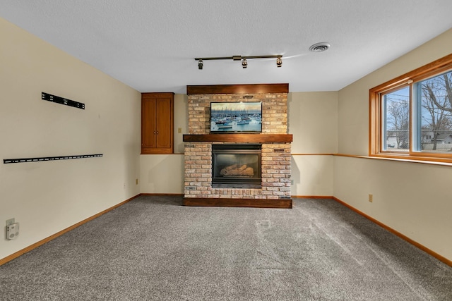 unfurnished living room featuring visible vents, baseboards, carpet, a fireplace, and a textured ceiling