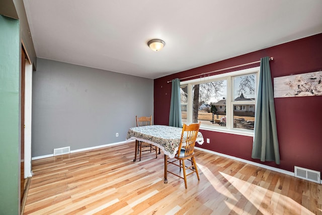 dining space featuring wood finished floors, visible vents, and baseboards