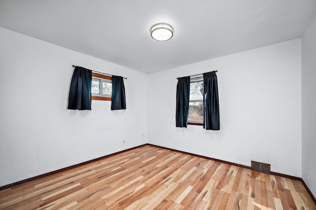 unfurnished room featuring light wood-style flooring, plenty of natural light, baseboards, and visible vents