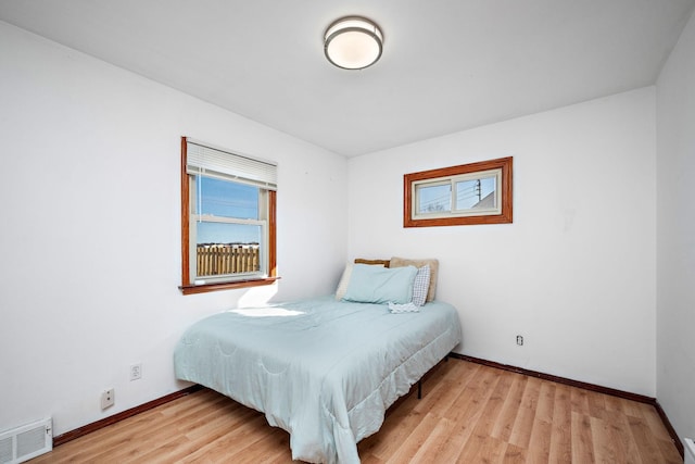 bedroom with light wood-style flooring, baseboards, and visible vents