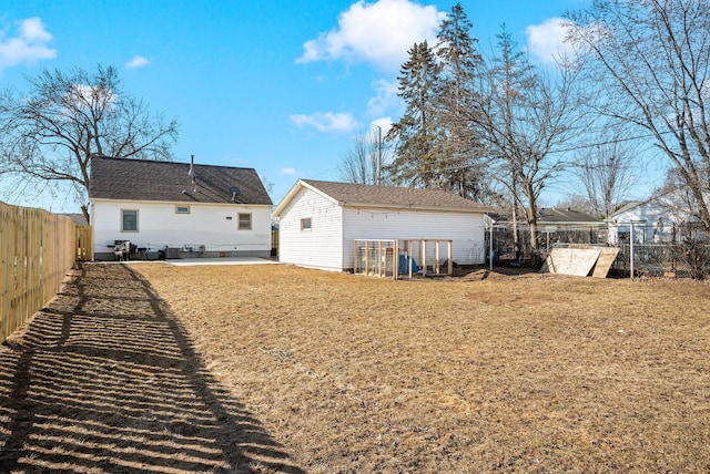 back of property with a patio area, a lawn, an outbuilding, and a fenced backyard