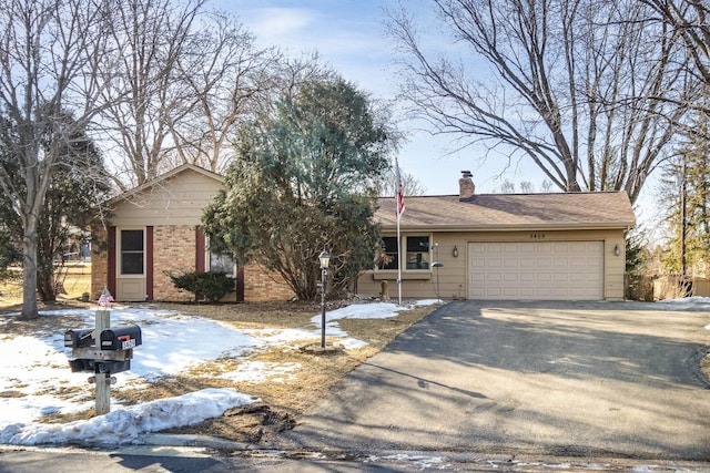 ranch-style home featuring a chimney, driveway, an attached garage, and brick siding