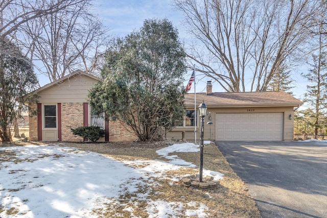 view of front of property with brick siding, an attached garage, a chimney, and driveway