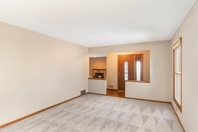 empty room with visible vents, a brick fireplace, carpet, and baseboards