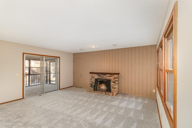 unfurnished living room with carpet flooring, a brick fireplace, and wooden walls