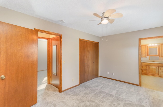 unfurnished bedroom with baseboards, ceiling fan, a sink, a closet, and light carpet