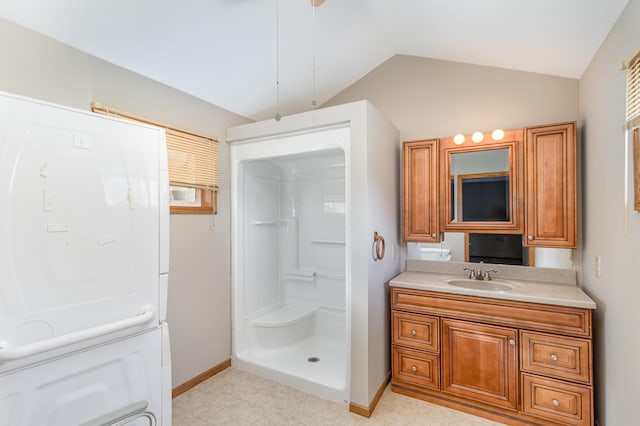 bathroom with vanity, vaulted ceiling, baseboards, and walk in shower