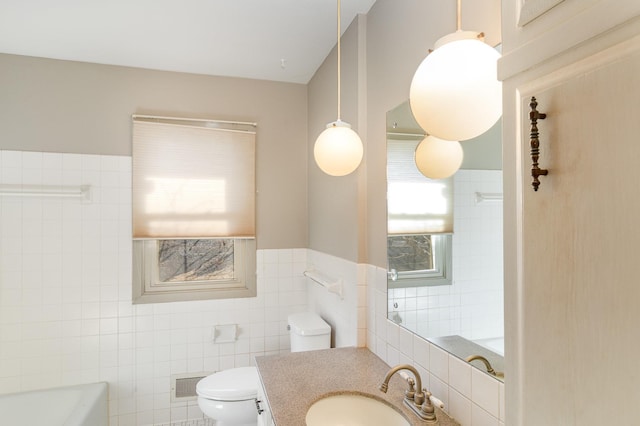 full bathroom featuring visible vents, toilet, a bathing tub, tile walls, and vanity