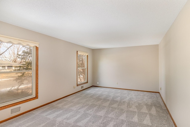 carpeted empty room with visible vents, baseboards, and a textured ceiling