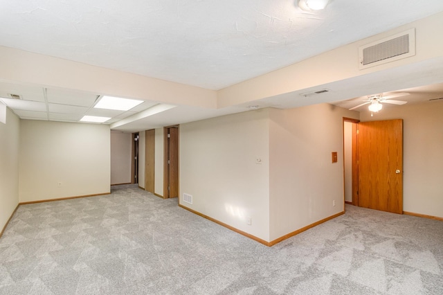 carpeted empty room with baseboards, visible vents, a drop ceiling, and ceiling fan