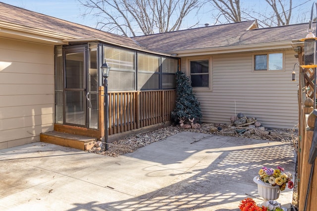 view of exterior entry with a patio and roof with shingles