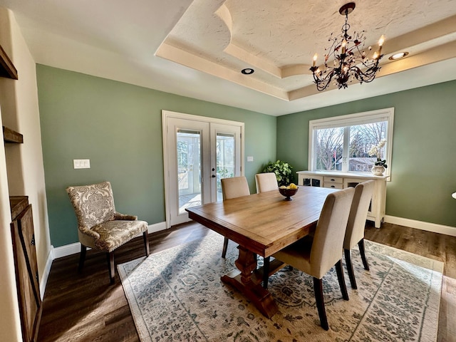 dining area with french doors, a raised ceiling, baseboards, and wood finished floors