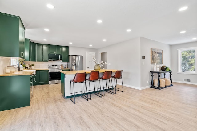 kitchen with light wood-type flooring, a sink, stainless steel appliances, light countertops, and green cabinetry