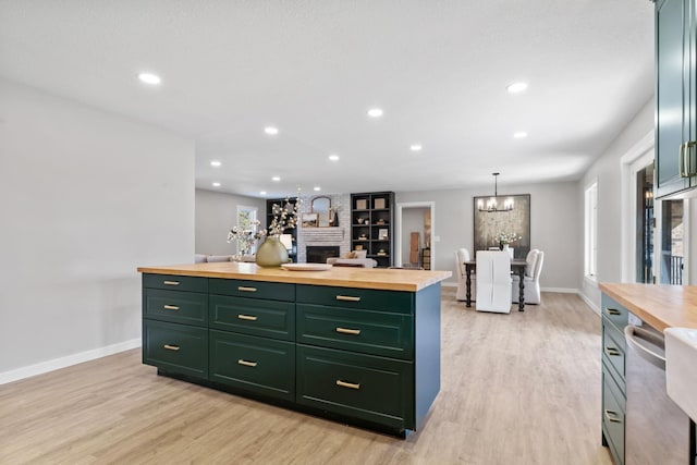 kitchen with green cabinetry, light wood-type flooring, stainless steel dishwasher, and butcher block countertops