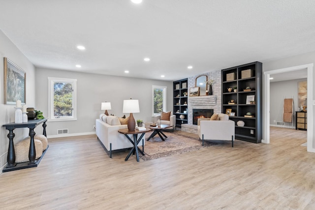 living area featuring a wealth of natural light, visible vents, a fireplace, and light wood-type flooring