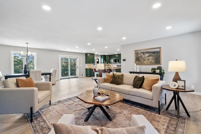 living area featuring recessed lighting, baseboards, an inviting chandelier, and light wood-style flooring