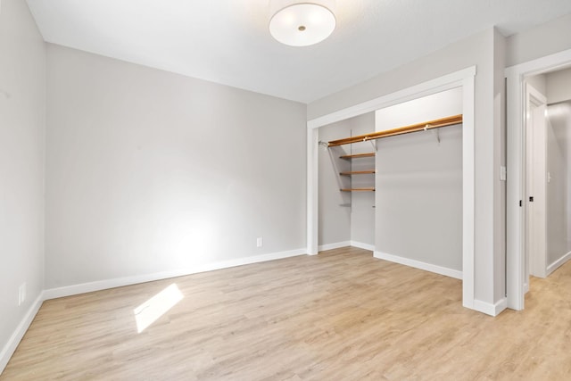 unfurnished bedroom with a closet, baseboards, and wood finished floors