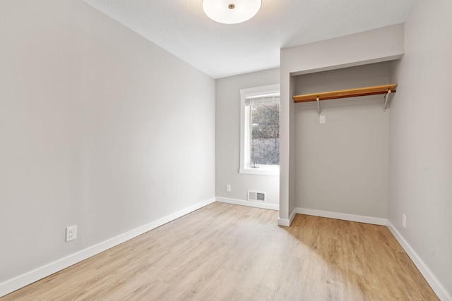 unfurnished bedroom with visible vents, baseboards, and wood finished floors