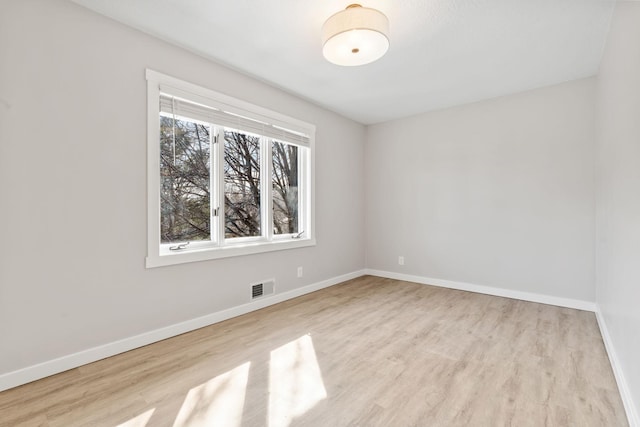 unfurnished room featuring wood finished floors, baseboards, and visible vents