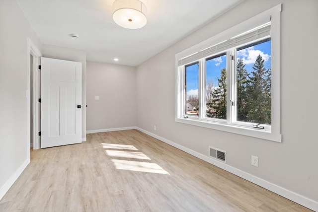 spare room with visible vents, baseboards, and wood finished floors