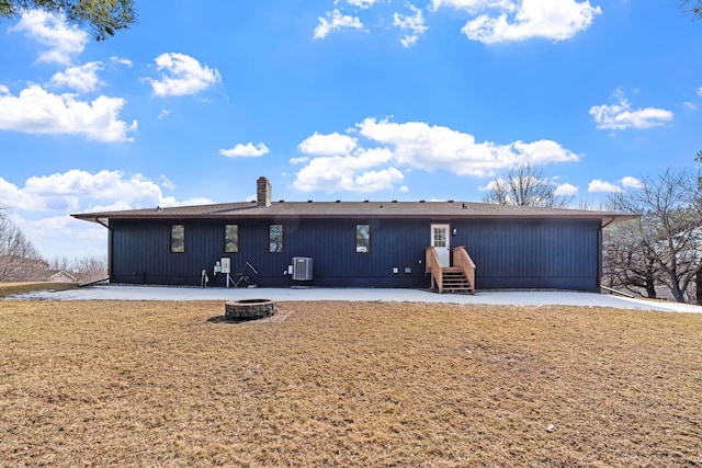 back of house featuring a fire pit, central AC unit, and a chimney