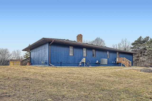 back of house featuring a yard, cooling unit, and a chimney